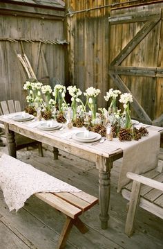 the table is set with white flowers and pine cones