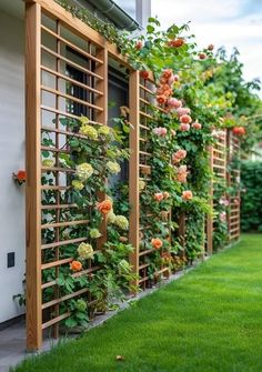 an outdoor garden with flowers growing on the fence and green grass in front of it