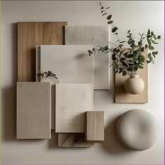 a white vase with some plants in it next to several different types of wood panels