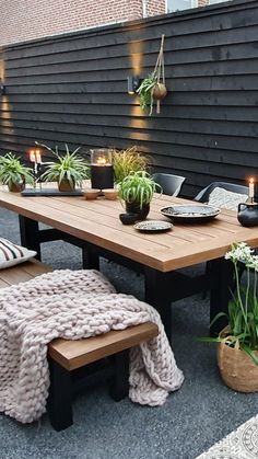 an outdoor dining table with candles and potted plants