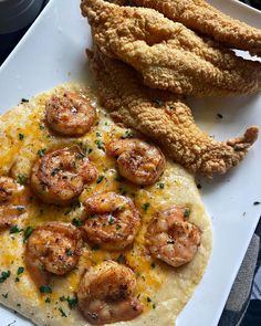 a white plate topped with shrimp and grits next to a piece of bread covered in cheese