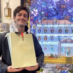 a man is holding a paper bag in front of a christmas tree and window display