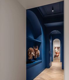 an empty hallway with blue walls and wooden floors is pictured in this image, there are sculptures on the wall