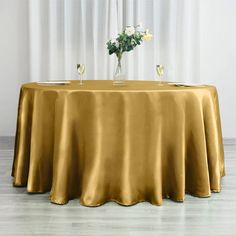 the table is covered with a gold cloth and two glasses are sitting on top of it