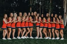 a group of women in red cheerleader outfits posing for a photo with each other