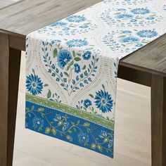 a blue and green table runner on top of a wooden table