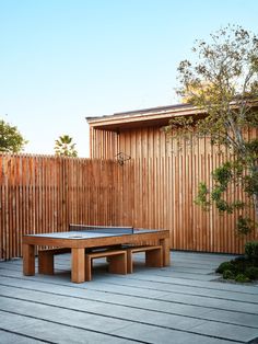 a ping pong table sitting on top of a wooden deck next to a fence