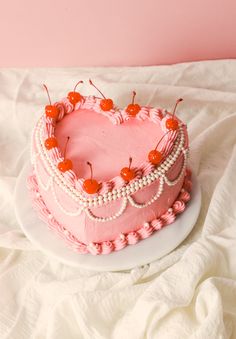 a pink heart shaped cake with cherries on top