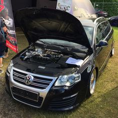 a black car with its hood open on the grass