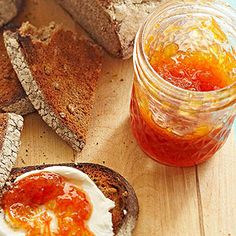 bread, jam and butter are on a cutting board next to a jar of jelly