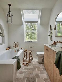 a bathroom that has a skylight above the toilet and bathtub in it, along with a rug on the floor