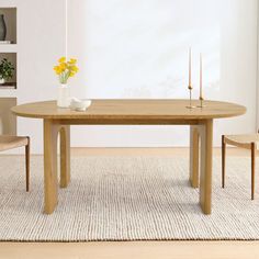 a wooden table sitting on top of a rug next to a chair and vase with flowers