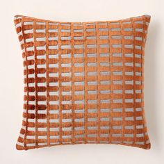 an orange and grey decorative pillow sitting on top of a white wall