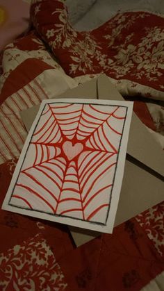 a spiderweave card is laying on top of a bed with red and white sheets