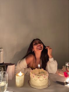 a woman sitting at a table in front of a cake with lit candles on it