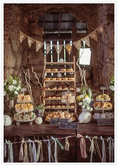 a table topped with lots of pastries and desserts next to a ladder covered in bunting