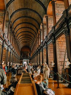 many people are sitting in the long room with bookshelves on either side of them