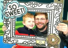 a man and boy are holding up a photo frame with a doughnut on it