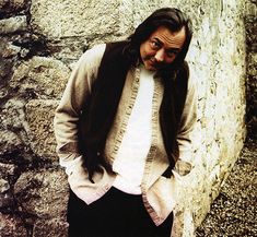 a man standing in front of a stone wall