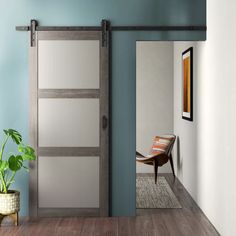 an open sliding door in a room with blue walls and wood flooring, along with a potted plant