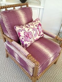 a purple chair with two pillows on it and a lamp in the corner behind it