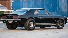 a black muscle car parked in front of a building