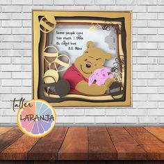 a winnie the pooh cutout in a frame on a wooden table next to a brick wall