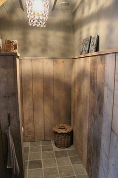 a bathroom with wooden walls and tile flooring next to a light hanging from the ceiling