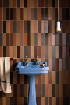 a blue sink sitting next to a wall with brown and tan tiles on the walls