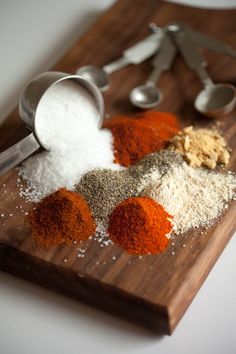 various spices on a wooden cutting board with measuring spoons