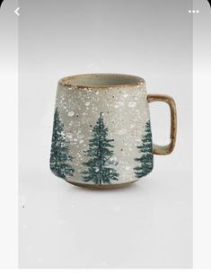 a white and green mug with trees on it