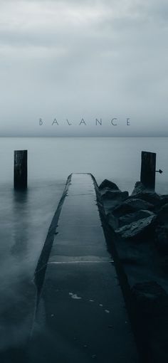 a long dock sitting on top of a body of water under a cloudy sky with the word balance above it