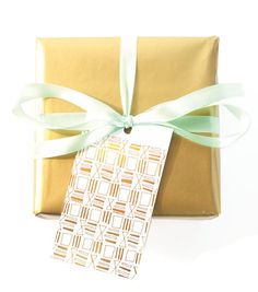 a present wrapped in gold paper with a green ribbon and tag on it's side