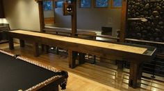 a pool table in the middle of a room with wood flooring and stone walls