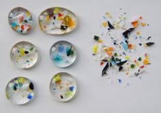 six glass cabochons with different designs and colors on them are shown next to a pile of confetti