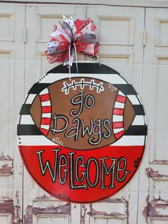 a welcome sign is hanging on the side of a building with an american football painted on it