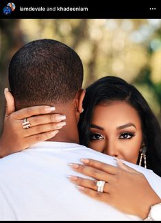 a man and woman embracing each other in front of trees