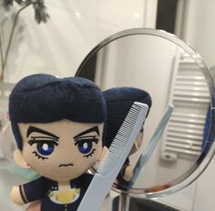 a stuffed doll with blue eyes holding a comb and looking at it in the mirror