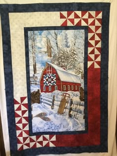 a quilted wall hanging with a barn in the snow on it's side