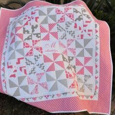 a pink and gray quilted placemat with monogrammed letters on it, sitting next to a palm tree