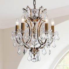 a crystal chandelier hanging from the ceiling in a room with white walls and windows