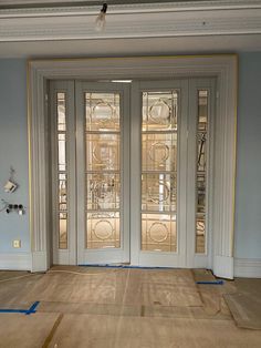 an empty room with two glass doors and blue tape on the floor