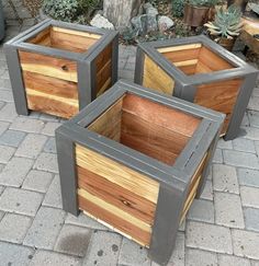 three wooden boxes sitting on top of a brick floor next to a potted planter