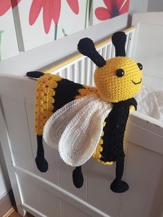 a crocheted stuffed bee hanging from the side of a crib