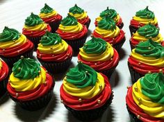 cupcakes decorated with green and red frosting on a white tableclothed surface