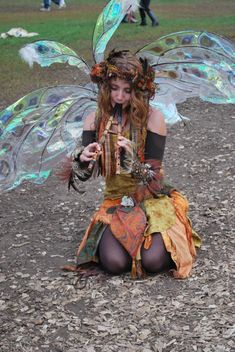 a woman dressed as a fairy sitting on the ground