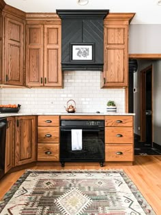 a kitchen with wooden cabinets and white tile backsplash, an area rug on the floor