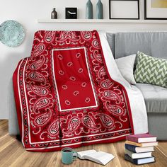 a black and red blanket sitting on top of a wooden floor next to a couch