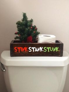 a toilet with a wooden sign that says stink tams tum