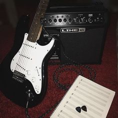 an electric guitar, amp and sheet music are laying on the floor next to each other